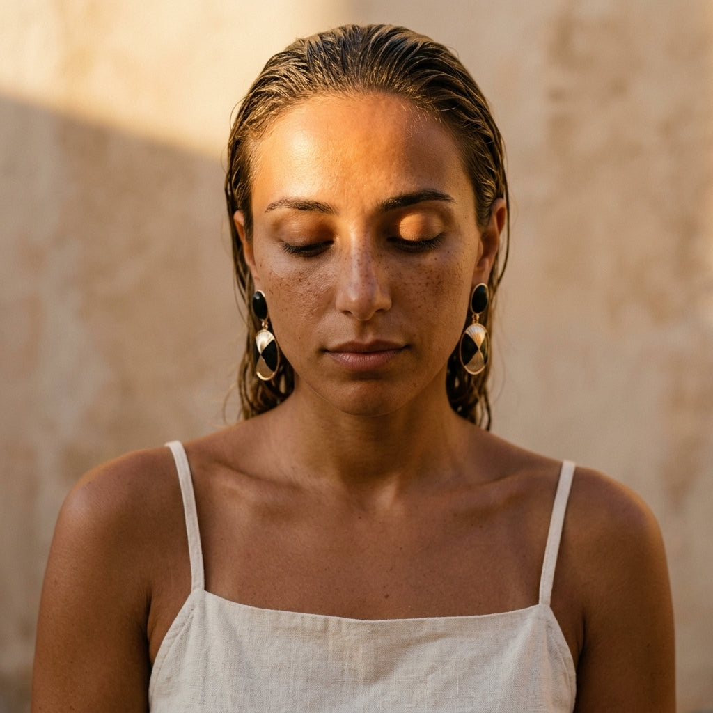 Eclipse earrings with black oval tops and gold fan-cut drops, on-ear view