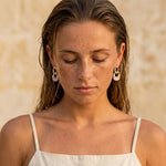 Gold-tone hoop earrings with oval pearl drops on model