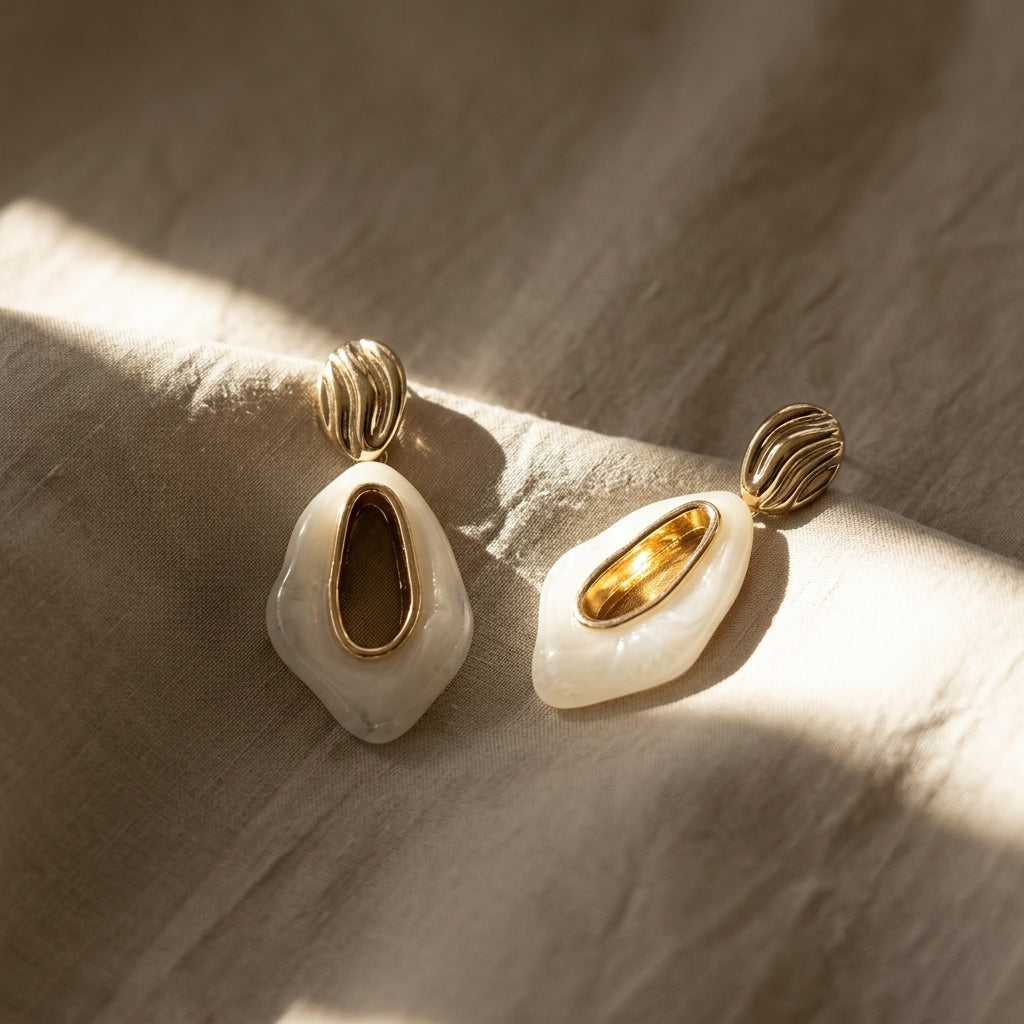 Pair of gold-tone teardrop earrings with white enamel, ridged hoops, and gold oval centers.