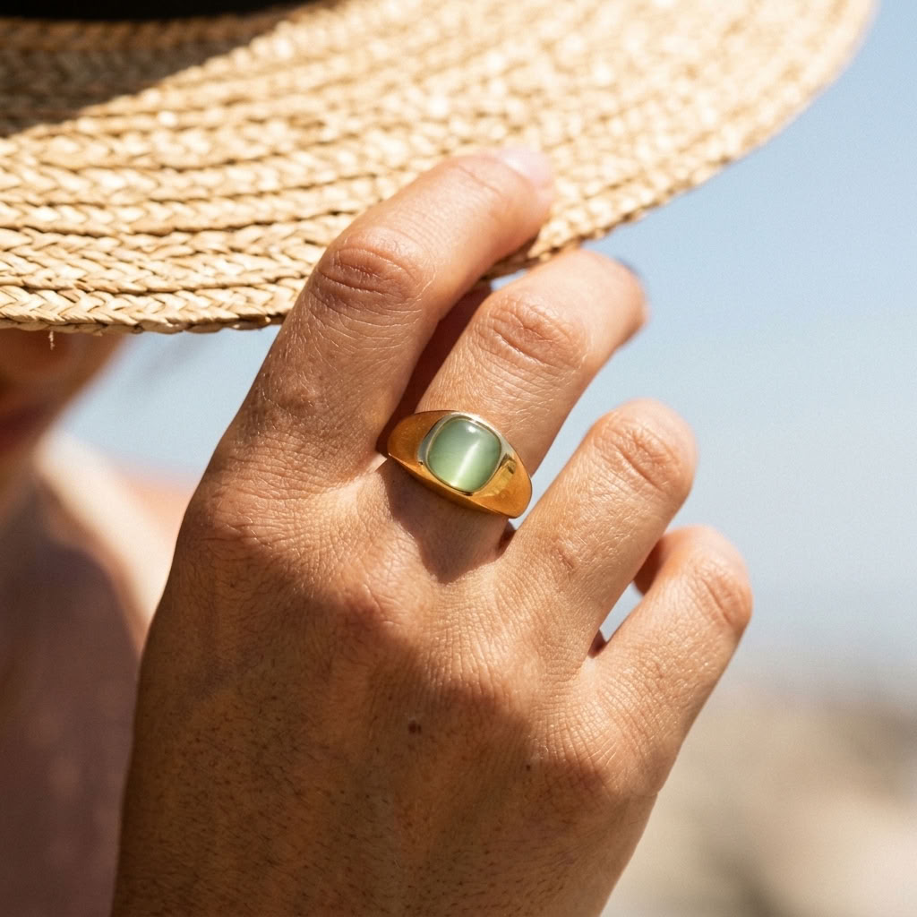 Gold-tone ring with oval green cabochon and wide gold band